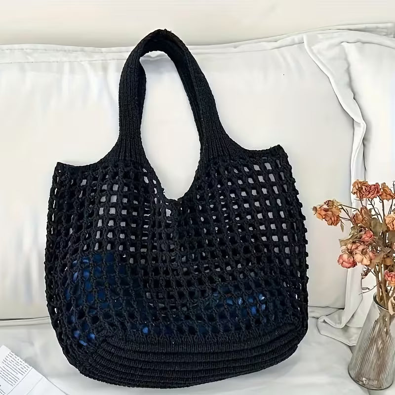 Bolsa tricotada preta posicionada em ambiente interno destacando seu design.