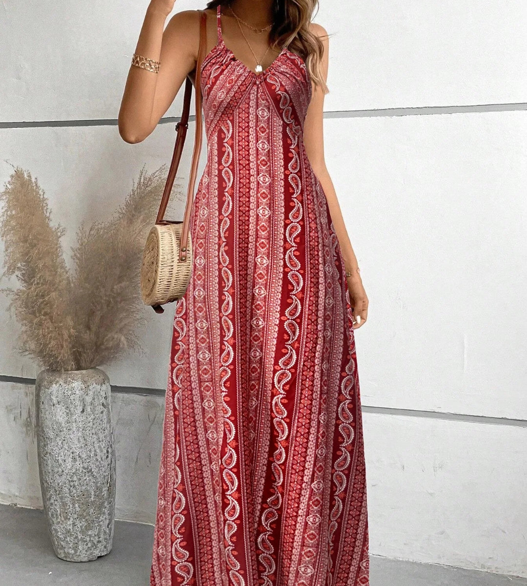 Mulher posando com o vestido longo vermelho Almería exibindo a padronagem ornamental rica em detalhes.