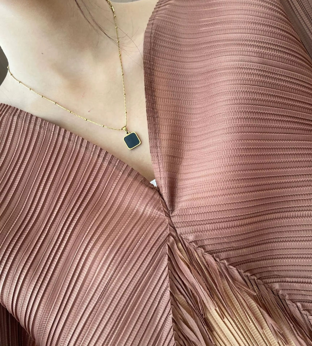 Detalhe da manga batwing e do decote em V no vestido café plissado  