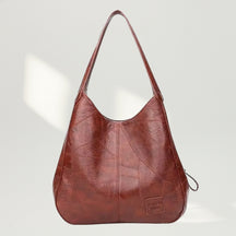 Vista frontal da Bolsa de Ombro Maré Vintage Brown com recortes geométricos e design hobo.