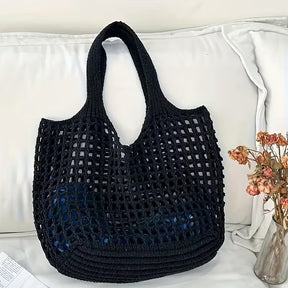 Bolsa tricotada preta posicionada em ambiente interno destacando seu design.