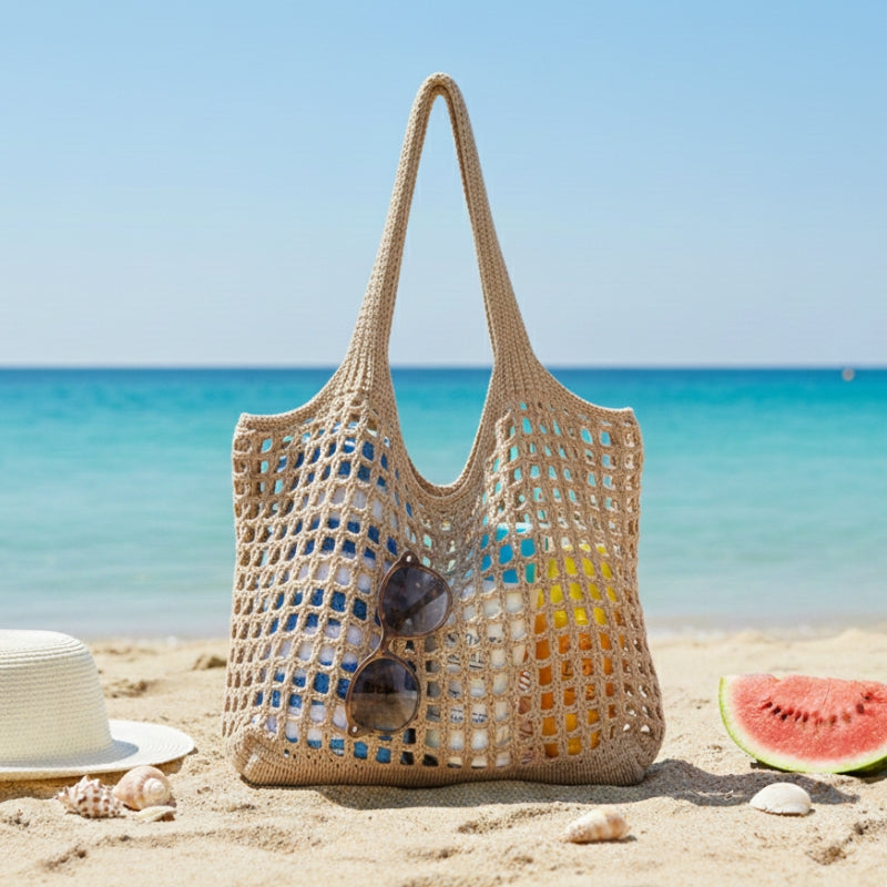 Modelo utilizando bolsa feminina tricotada em rede branca durante passeio na praia.