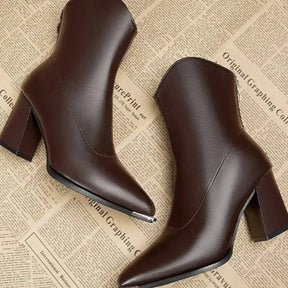 Bota feminina preta de cano curto com bico fino, salto bloco e acabamento sofisticado para looks elegantes.