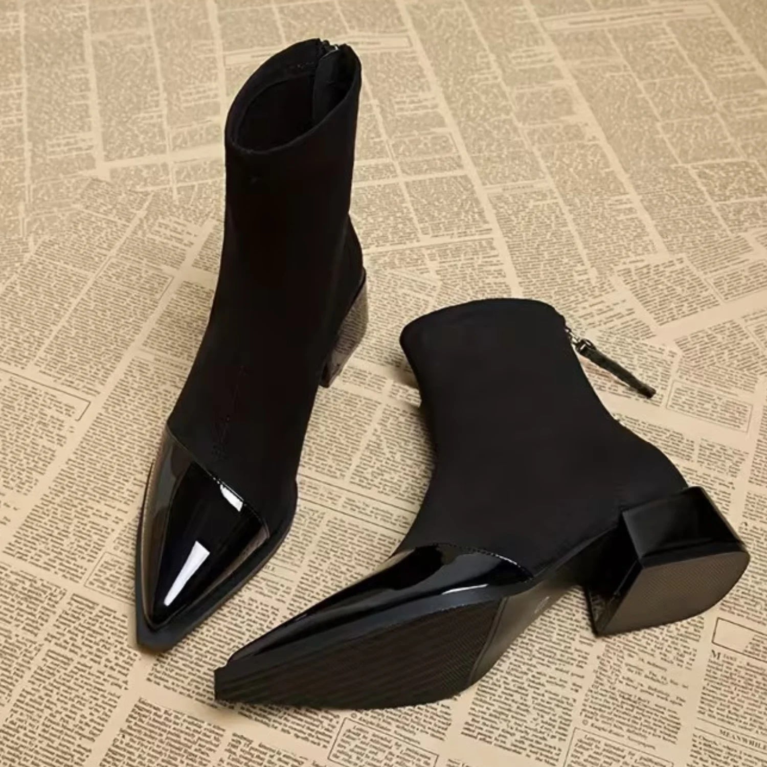 Par de botas femininas pretas com bico fino em verniz, cano curto, salto bloco e fechamento traseiro.