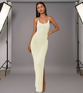 Mulher posando com vestido longo de tricô e óculos de sol em cenário de luxo à beira-mar.