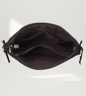 Interior da bolsa preta aberto exibindo as divisórias internas e o forro resistente.