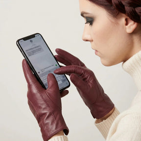 luva feminina bordeaux utilizando smartphone com tecnologia touch screen funcional