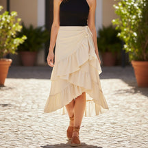 Mulher usando saia midi assimétrica bege com babados e amarração lateral modelo Eternal Grace em vista frontal