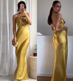 Look de gala feminino com vestido longo dourado e acessórios minimalistas de luxo.