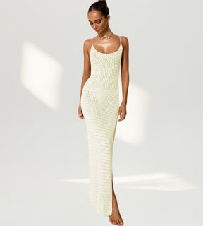 Vista frontal de vestido longo amarelo em tricô com fenda lateral profunda em ambiente ensolarado.