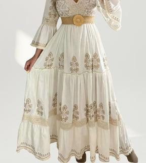 Mulher usando o Vestido Longo Valência off-white com estampas ornamentais em ambiente ensolarado de jardim.
