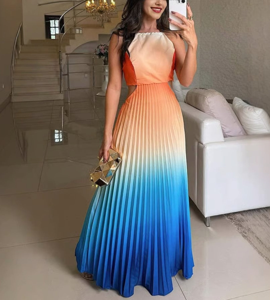 Modelo posando com o vestido longo Marbella em degradê laranja e azul com brilho acetinado.