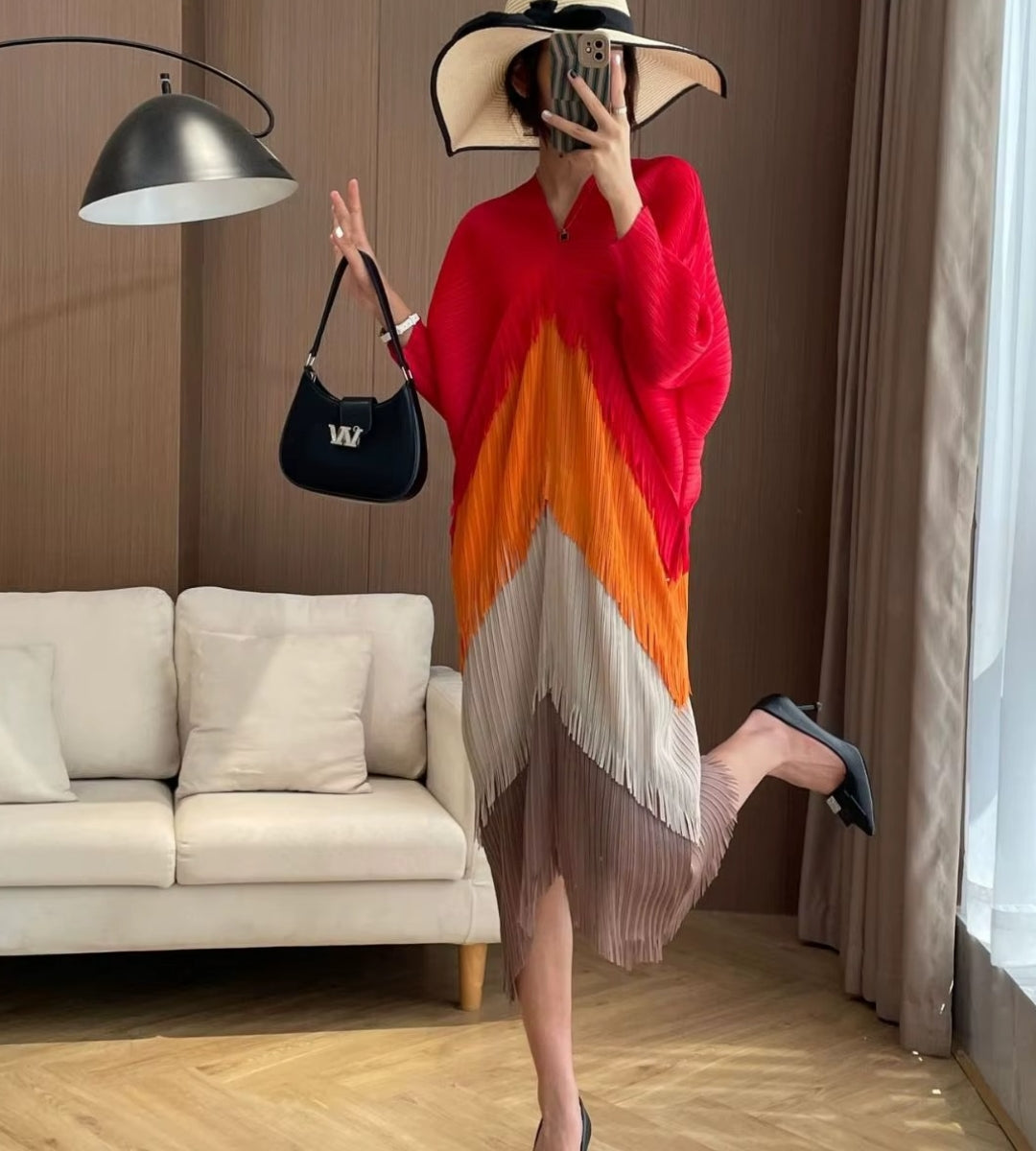 Mulher posando com o vestido midi laranja Biarritz exibindo o caimento fluido da manga batwing.