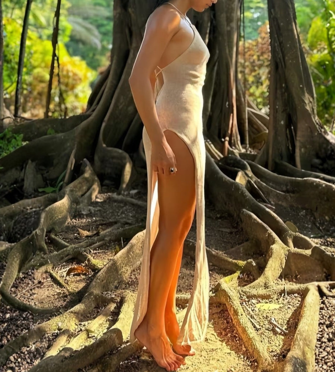 Look feminino sofisticado com vestido longo de tricô e fenda lateral profunda.