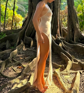 Look feminino sofisticado com vestido longo de tricô e fenda lateral profunda.
